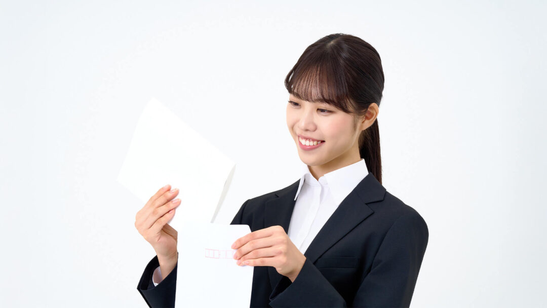 履歴書を封筒にしまう女性の画像